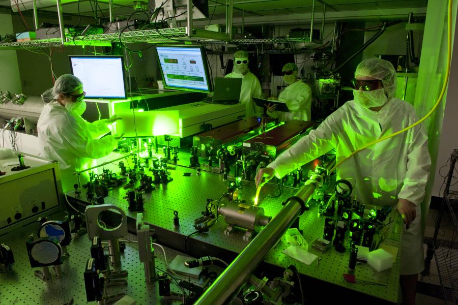 Physicists working in laser lab illuminated by green laser scatter